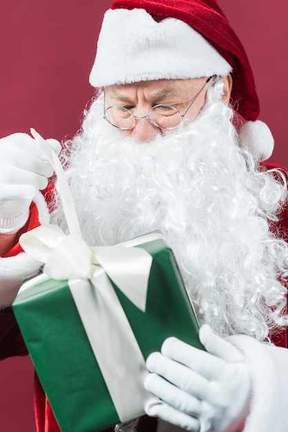 Santa Claus in den Gläsern mit grüner Geschenkbox in den Händen