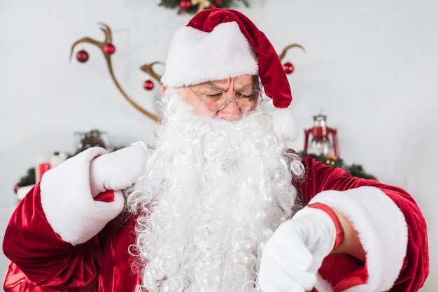 Santa Claus in den Gläsern Zeit auf Armbanduhr überprüfend