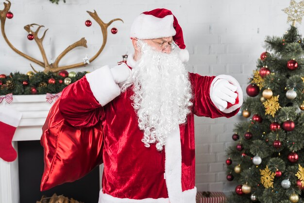 Santa Claus mit dem Sack, der Zeit auf Armbanduhr überprüft