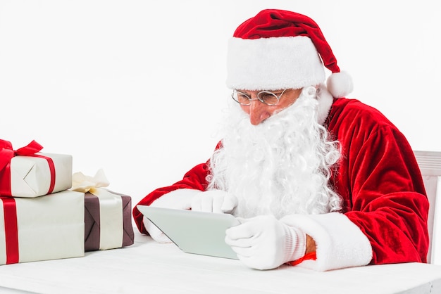 Santa Claus mit Tablette bei Tisch