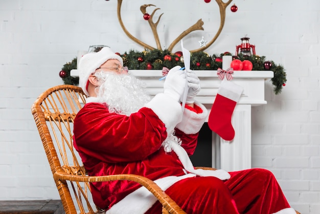 Santa sitzt in Rocker mit Papier und Stift