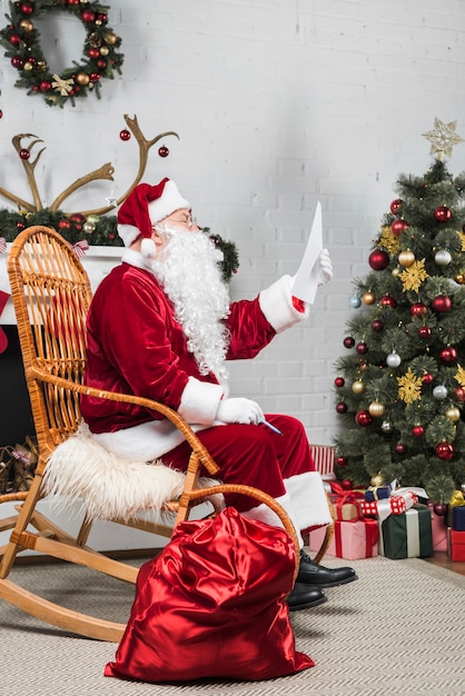 Santa sitzt in Rocker und liest Wunschliste