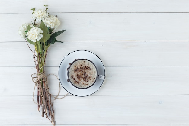 Kostenloses Foto satz blumen und kaffee in einer tasse auf einem hölzernen hintergrund. draufsicht.