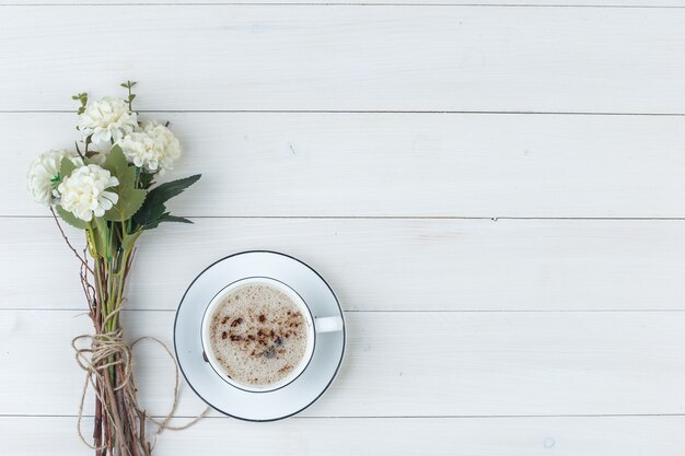 Satz Blumen und Kaffee in einer Tasse auf einem hölzernen Hintergrund. Draufsicht.