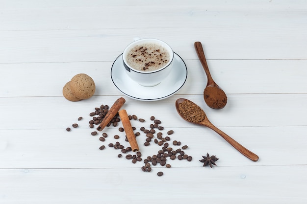 Satz gemahlener Kaffee, Gewürze, Kaffeebohnen, Kekse und Kaffee in einer Tasse auf einem hölzernen Hintergrund. High Angle View.