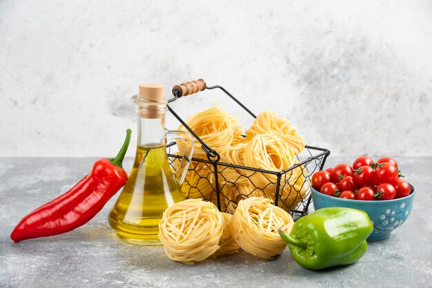 Satz Pilze, natives Olivenöl extra, Nudeln, Kirschtomaten und Chilischoten auf einem Stück Marmor.