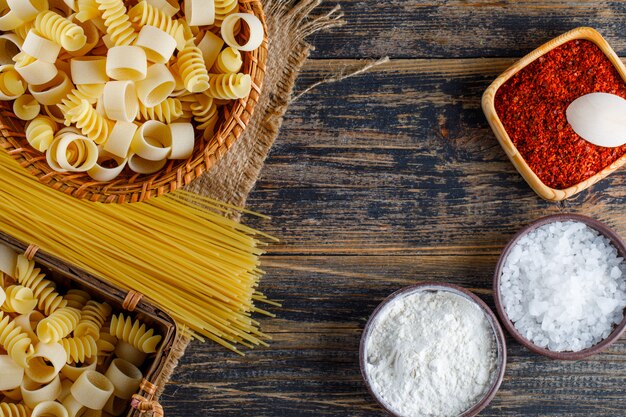 Satz Salz, rote Gewürze, Spaghetti und Makkaroni-Nudeln auf einem hölzernen Hintergrund. flach liegen.