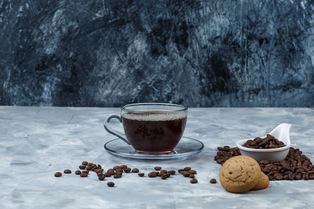 Satz Tasse Kaffee, Kekse und Kaffeebohnen in einem weißen Porzellankrug