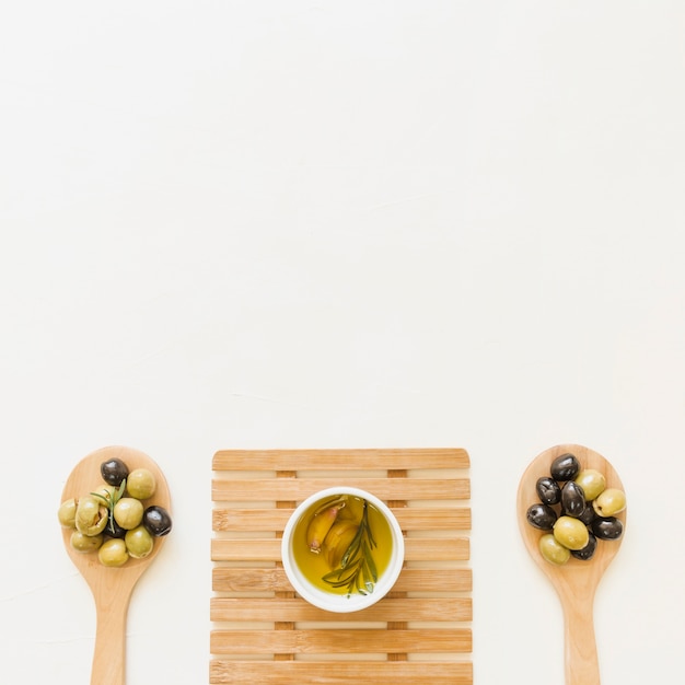 Sauciere auf heißem Pad mit Oliven in den Löffeln