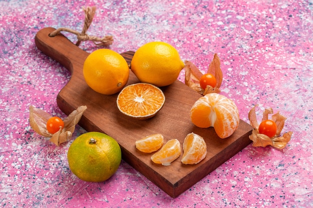 Saure frische Mandarinen der Vorderansicht mit Zitronen auf rosa Hintergrund.