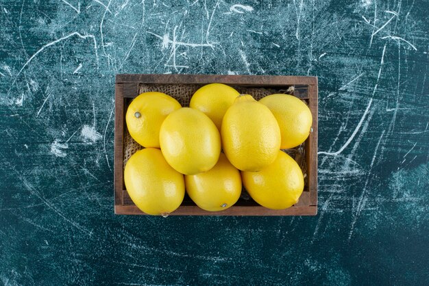 Saure gelbe Zitronen in Holzkiste.
