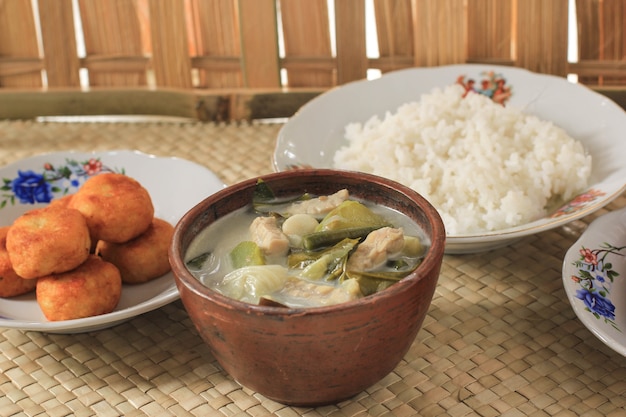 Sayur lodeh oder gemüse mit kokosmilchsuppe. traditionelles indonesisches kulinarisches essen aus java in traditioneller schüssel serviert auf bambustisch. selektiver fokus
