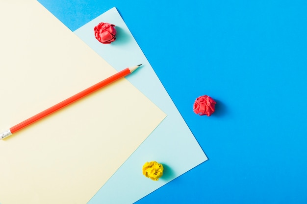 Scarp Bleistift mit zerknittertes Papier auf Kartenpapier über blauem Hintergrund