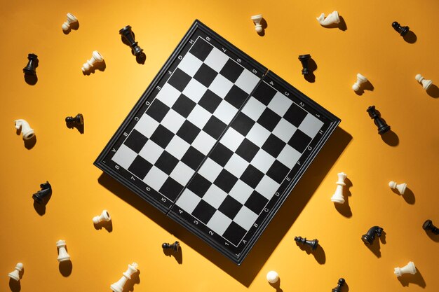 Schachfiguren und Schachbrett auf gelbem Hintergrund