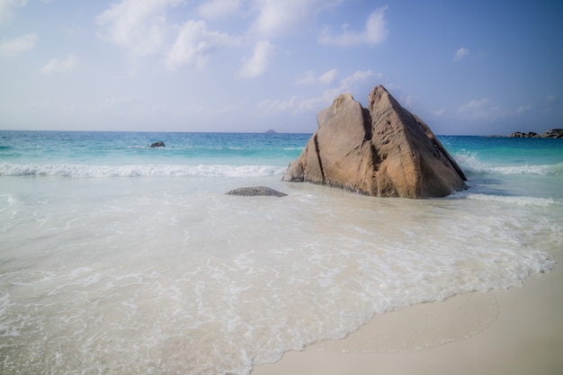 Scharfer felsen an einem strand, umgeben vom meer unter dem sonnenlicht in anse lazio in praslin, seychellen