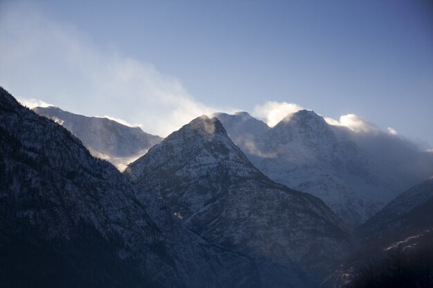 Schattenbild der felsigen Berge bedeckt mit Schnee und Nebel während des Winters