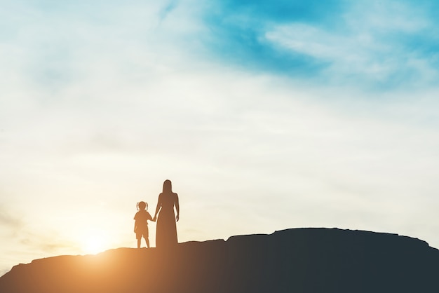 Schattenbild der Mutter mit ihrer Tochterstellung und -sonnenuntergang