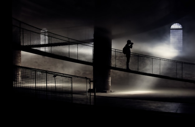 Schattenbild der Person, die auf Brücke beim Fotografieren steht