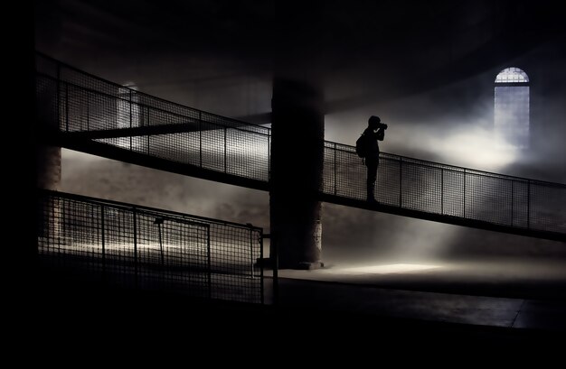 Schattenbild der Person, die auf Brücke beim Fotografieren steht