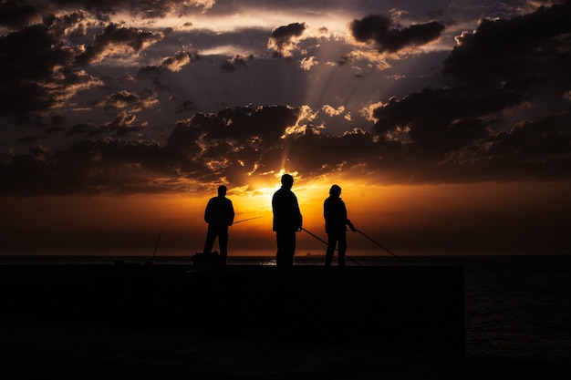 Schattenbild des Fischers am Strand bei Sonnenuntergang