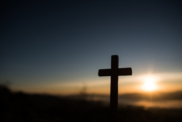 Schattenbild des katholischen Kreuzes und des Sonnenaufgangs