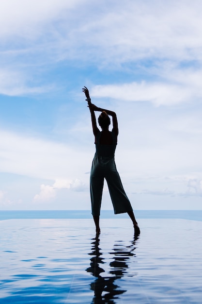 Kostenloses Foto schattenbild einer frau, die auf der wasseroberfläche des unendlichkeitspools einer teuren reichen luxusvilla auf einem berg mit meerblick geht