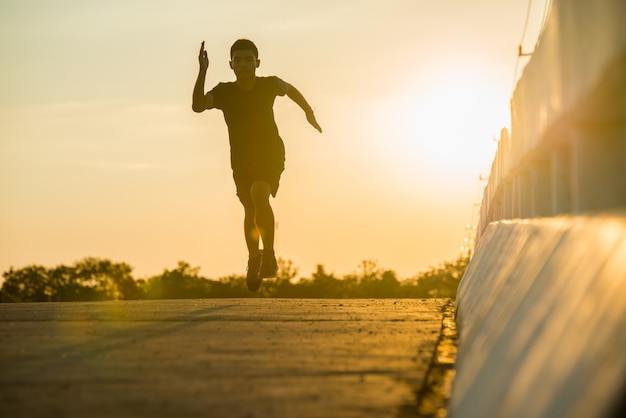 Schattenbild eines jungen Eignungsmannes, der auf Sonnenaufgang läuft