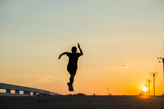 Schattenbild eines jungen Eignungsmannes, der auf Sonnenaufgang läuft