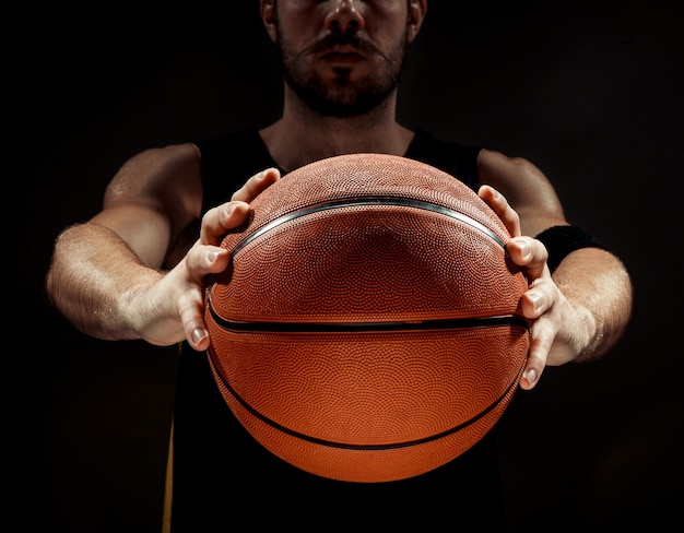 Kostenloses Foto schattenbildansicht eines basketballspielers, der basketball auf schwarzem hintergrund hält