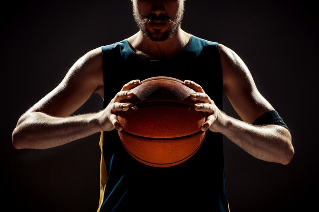 Schattenbildansicht eines Basketballspielers, der Basketball auf Schwarzraum hält