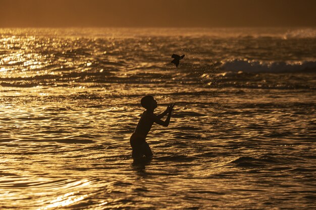 Schattenbildaufnahme eines Jungen, der am Strand spielt