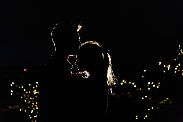 Schattenbilder eines reizenden jungen Paares, das auf der Dachspitze in der Nacht steht