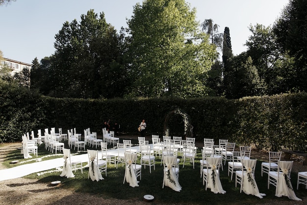 Schauen Sie von hinten auf weiße Stühle, die für Hochzeitszeremonie angeordnet sind