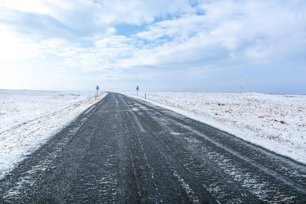 Schauriger Blick auf eine unbefestigte Landstraße zwischen schneebedeckten Feldern in Island