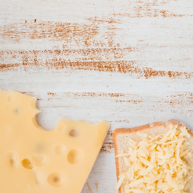 Scheibe und geriebener Emmentalerkäse auf hölzernem Schreibtisch