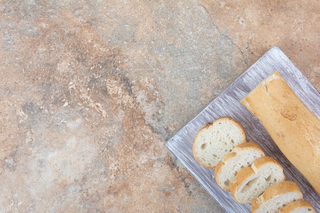 Scheiben Baguettebrot auf Holzbrett