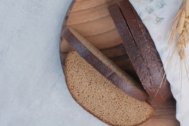 Scheiben frisches Schwarzbrot auf Holzbrett.