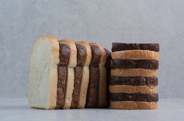 Scheiben frisches Weiß- und Schwarzbrot auf Marmorhintergrund.