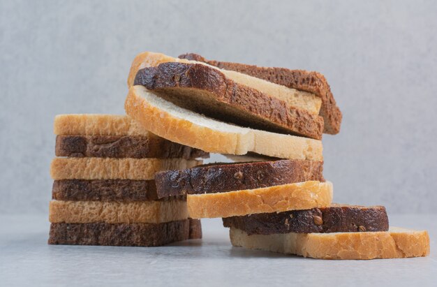 Scheiben frisches Weiß- und Schwarzbrot auf Marmorhintergrund.