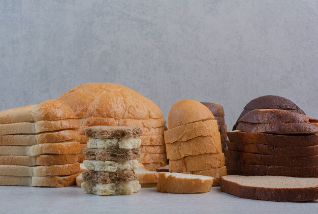 Scheiben frisches Weiß- und Schwarzbrot auf Marmorhintergrund.