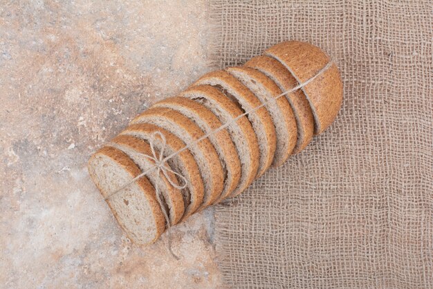 Scheiben Roggenbrot auf Marmoroberfläche mit Sackleinen