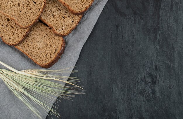 Scheiben Schwarzbrot mit Weizen auf grauem Hintergrund.