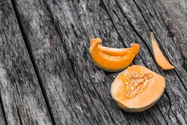 Scheiben und halbiert von Moschus Melone auf einem alten Holztisch