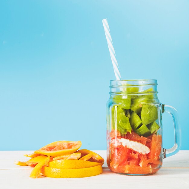 Scheiben von frischen Früchten im Glas gegen blaue Wand