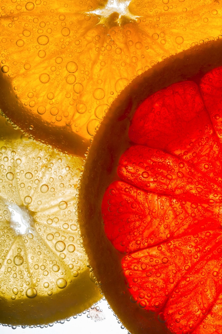 Kostenlose Foto scheiben von orange, zitrone und grapefruit liegen in wasser voller luft