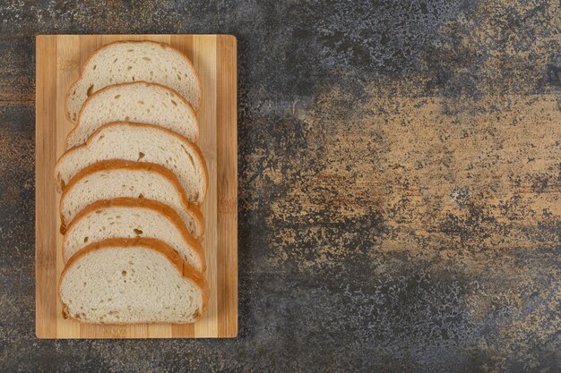 Scheiben Weißbrot auf Holzbrett