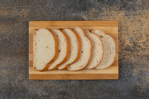 Scheiben Weißbrot auf Holzbrett.