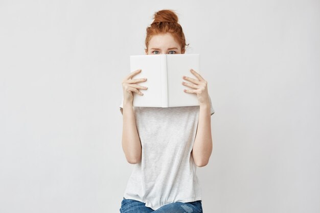 schicke Frau versteckt Gesicht hinter Buch.