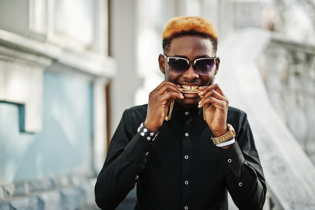 Schicker, gutaussehender Afroamerikaner in schwarzem Hemd mit goldener Kette und Sonnenbrille