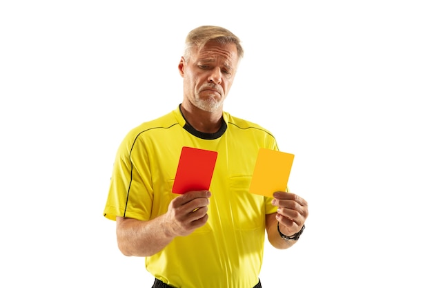 Schiedsrichter, der einem Fußball- oder Fußballspieler eine rote und gelbe Karte zeigt, während er an der weißen Wand spielt. Konzept des Sports, Regelverletzung, kontroverse Themen, Überwindung von Hindernissen.